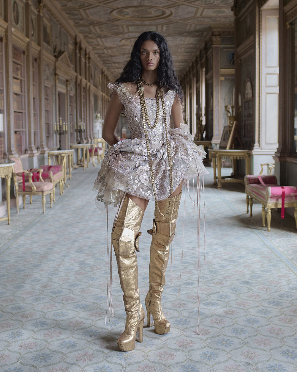 Aurelia embroidered bridal mini with exaggerated hips, long ribbons and gold thigh-high platform boots in an ornate gallery.